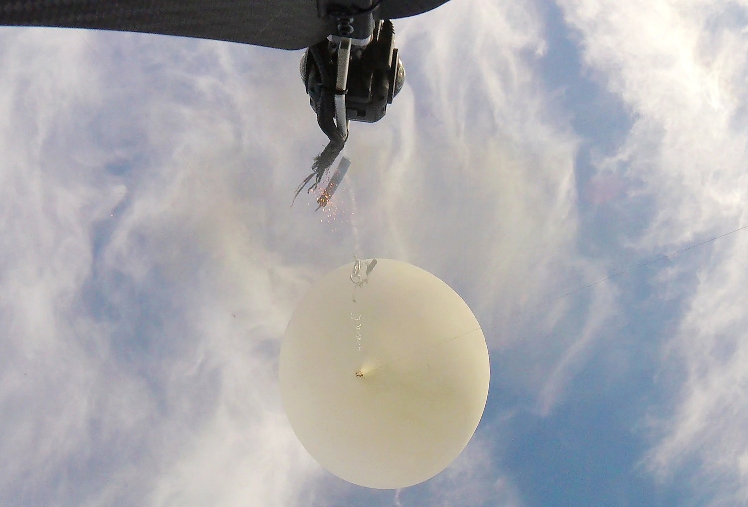 Secondary camera view of the cutdown pyro at the moment of firing. The main tether is already recoiling upward like a spring. The primary 360 camera is visible at top center.